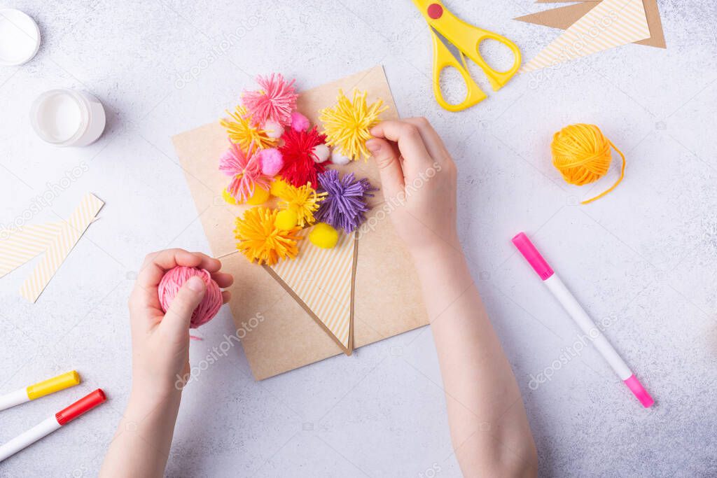 Small child doing a bouquet of flowers out of coloured paper and coloured knitting balls for mom. Simple gift idea. view top, copy space