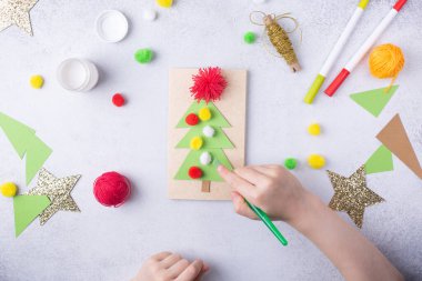 Çocuk bir tebrik kartı hazırlıyor. Noel kâğıdı kolajı. Çocuklar için sanat projeleri