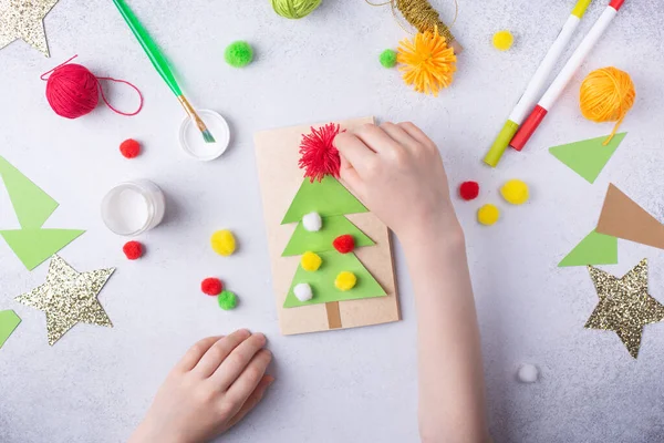 Το παιδί κάνει μια ευχετήρια κάρτα Χριστουγεννιάτικο κολάζ χαρτί. Παιδική τέχνη έργο τέχνης για τα παιδιά — Φωτογραφία Αρχείου