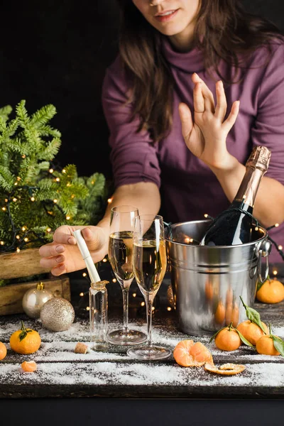 Meisje maakt een kerstwens en zet het in kleine glazen fles en kruisvingers, Champagne in metalen emmer achter — Stockfoto