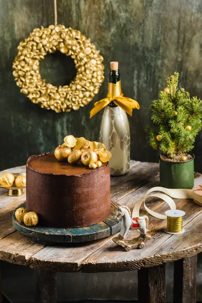 Pastel de Navidad de chocolate con champán de decoración de oro detrás del estilo rústico — Foto de Stock