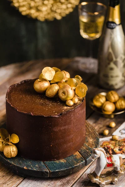 Pastel de chocolate con la decoración de oro champán detrás de estilo rústico — Foto de Stock