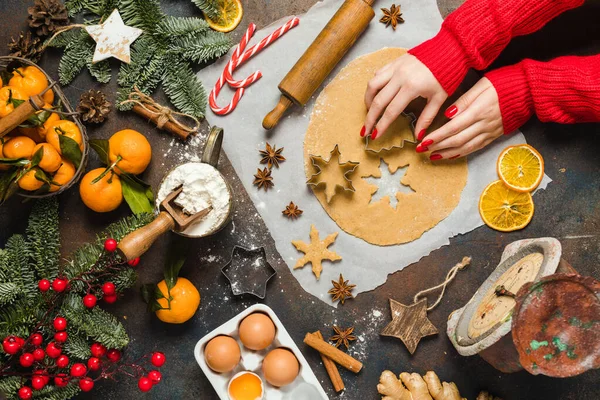 Feiertagsspeisen. Zutaten für weihnachtliche Ingwerplätzchen, kleine Bäume und Schneeflocken. Frauenhand mit roten Nägeln — Stockfoto