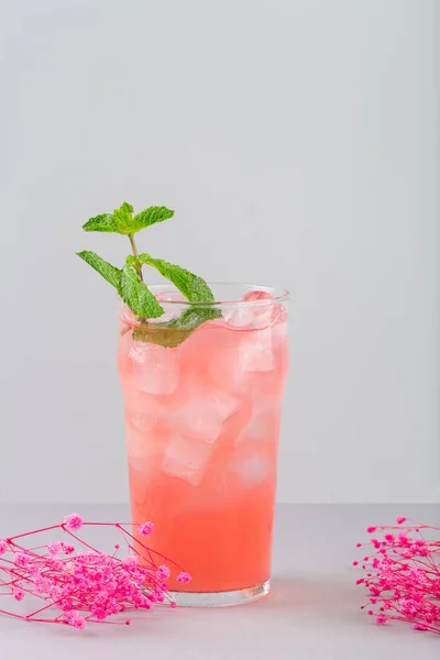 Refreshing cocktail rose with grape syrup and mint rose flowers next to the glass on grey — Stock Photo, Image