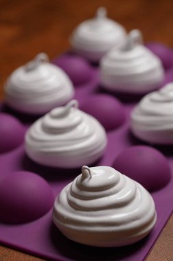 Profesyonel pasta şefi, parlak Fransız kremasını fırın tepsisine koydu. Düşük sıcaklıkta pişirmeye hazır. Klasik beyaz kremalı, mükemmel kıvrımlı, silikon hasırlar ya da fırın kağıdı üzerinde düzenli sıralanmış. Taze ev yapımı tatlı.