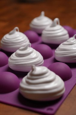 Profesyonel pasta şefi, parlak Fransız kremasını fırın tepsisine koydu. Düşük sıcaklıkta pişirmeye hazır. Klasik beyaz kremalı, mükemmel kıvrımlı, silikon hasırlar ya da fırın kağıdı üzerinde düzenli sıralanmış. Taze ev yapımı tatlı.