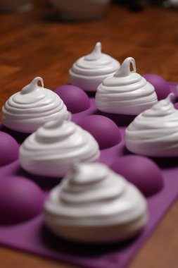 Profesyonel pasta şefi, parlak Fransız kremasını fırın tepsisine koydu. Düşük sıcaklıkta pişirmeye hazır. Klasik beyaz kremalı, mükemmel kıvrımlı, silikon hasırlar ya da fırın kağıdı üzerinde düzenli sıralanmış. Taze ev yapımı tatlı.