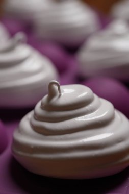 Profesyonel pasta şefi, parlak Fransız kremasını fırın tepsisine koydu. Düşük sıcaklıkta pişirmeye hazır. Klasik beyaz kremalı, mükemmel kıvrımlı, silikon hasırlar ya da fırın kağıdı üzerinde düzenli sıralanmış. Taze ev yapımı tatlı.