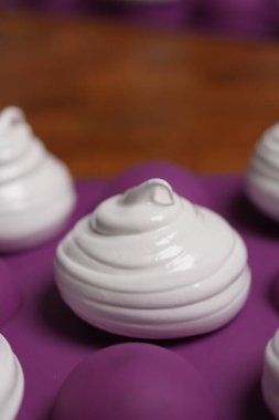 Profesyonel pasta şefi, parlak Fransız kremasını fırın tepsisine koydu. Düşük sıcaklıkta pişirmeye hazır. Klasik beyaz kremalı, mükemmel kıvrımlı, silikon hasırlar ya da fırın kağıdı üzerinde düzenli sıralanmış. Taze ev yapımı tatlı.