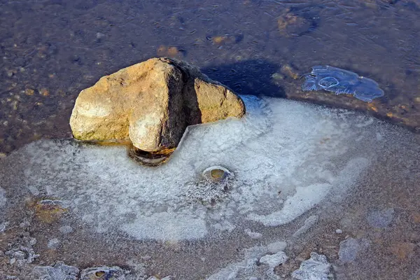 Sudaki bir kayanın en üst görüntüsü. Soğuk su kısmen donmuş..