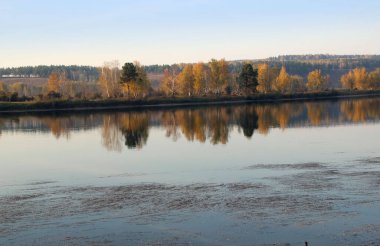 Büyük bir ayna gibi sonbahar manzarasını yansıtan sakin nehir yüzeyine bakın..