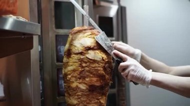 Bir aşçı shawarma, gyros, doner kebap yapmak için et keser..