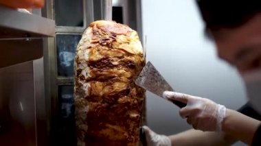 Bir aşçı shawarma, gyros, doner kebap yapmak için et keser..
