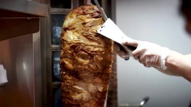 Bir aşçı shawarma, gyros, doner kebap yapmak için et keser..