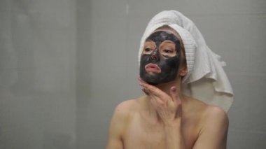 Yetişkin bir kadın yüzüne krem maske takar.