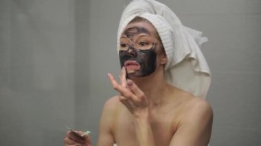 Yetişkin bir kadın yüzüne krem maske takar.