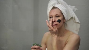 Yetişkin bir kadın yüzüne krem maske takar.