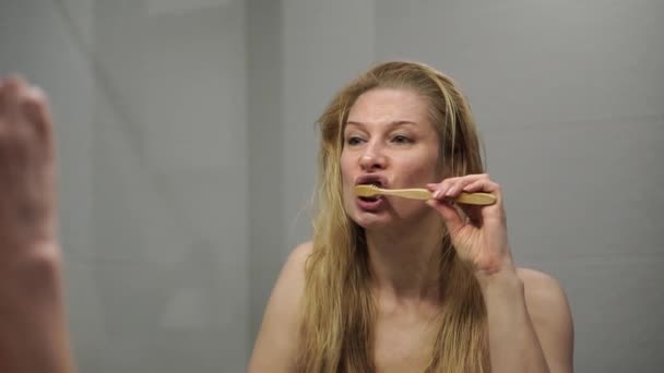 Mulher adulta escovando os dentes com uma escova de madeira — Vídeo de Stock