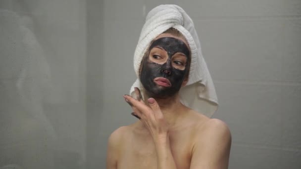 Una mujer adulta se aplica una máscara de crema en la cara — Vídeo de stock