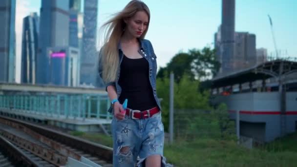 Young blonde woman walks on the railroad tracks in the city — Stock Video