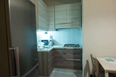 Modüler köşeli mutfağın gri ve kahverengi rengini gören kabin altı ışığı dikkat çeker..