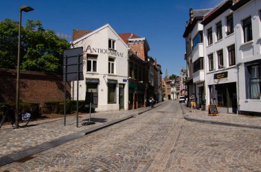 Mechelen, Belçika. Ağustos 2019. Güneşli güzel bir yaz gününde, tarihi merkezde bir cadde. Taş bloklu cadde ve tuğla evler bizi geçmişe götürüyor..