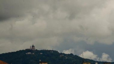 Torino, Piedmont, İtalya. Mayıs 2019. Baharda yağmurlu bir günde, Superga Bazilikası 'nın arkasından kara bulutlar tepeyi geçer ve Torino' ya doğru iner. 4K çözünürlüğündeki zaman aşımı.