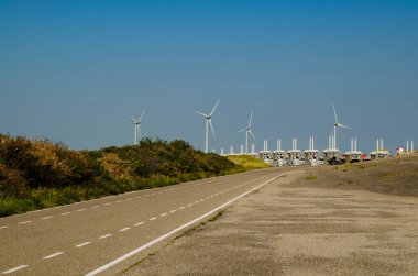Hollanda, Ağustos 2019. Zeeland 'de, rüzgâr tarlaları, deniz sularının akışını yöneten ve bölgeyi güvence altına alan büyük baraj için kurulmuştur..
