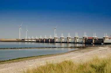 Hollanda, Ağustos 2019. Zeeland 'de, rüzgâr tarlaları, deniz sularının akışını yöneten ve bölgeyi güvence altına alan büyük baraj için kurulmuştur..