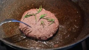 Ev hayatı sahneleri: biberiyeyle süslenmiş bir hamburger yemek yaparken çatalla kontrol edilir.