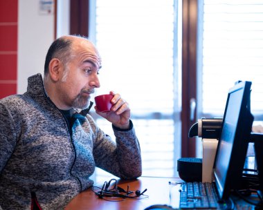 Orta yaşlı beyaz bir adam evden kahve içerken bilgisayar monitöründe yazan bir uyarıya hoş bir şekilde şaşırır..
