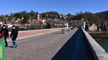 San Mauro, İtalya, Şubat 2021. Koronavirüs zamanında ev hayatından kaçmak: kış boyunca güneşli bir gün sizi evden çıkarır. Yaya köprüsünü insanlar ve bisikletler geçiyor..