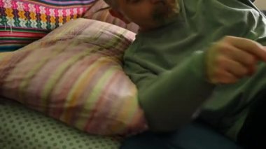 Ev hayatı sahnesi: Orta yaşlı beyaz bir adam dinlenmek için çift kişilik yatağa uzanıyor, yastığını ayarlıyor ve gözlerini kapıyor, derin derin nefes alıyor. Sağlık istirahatı ve refleks kavramı.