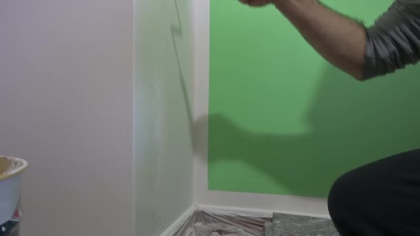 在滚筒上拍了近照作画 中年男人把它放在墙上 你可以看到一些油漆滴在滚筒上 家庭翻新概念 家庭生活 — 图库视频影像