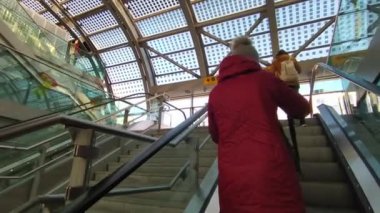 Torino, Piedmont, İtalya. Mart 2021. Porta Susa tren istasyonu. Yürüyen merdivenler sokak seviyesini yer altı seviyesine bağlıyor. Bir kadın bir nesneyi almak için sırt çantasını çıkarır. 30fps 4K video