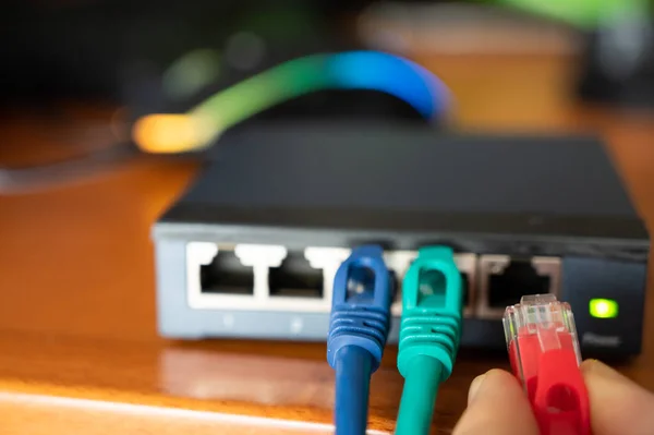 Bir yönlendiricinin yakın plan görüntüsü: üç kırmızı, yeşil ve mavi ethernet kablosunun bağlantıları test edilir. Kablolama kavramı, internet ağı, İnternet, bakım ve işletim ile çalışma.
