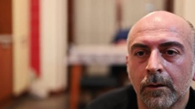 Evde zorlu bir spor salonunu yeni bitirmiş orta yaşlı beyaz bir adamın portresi: Soluklanıyor ve yüzünü havluyla siliyor, bitkin ve terli. Bulanık arkaplan.