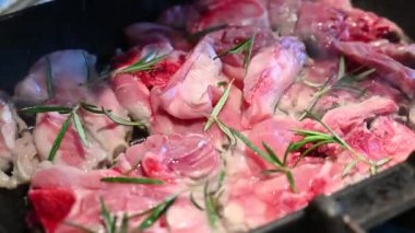 Çiğ kuzunun pişirildiği tavanın yakın çekim görüntüleri. Biberiye iğneleri baharat olarak bilinir. Paskalya için tipik Akdeniz mutfağı yemeği. Tuz öğütücüyle eklenir..