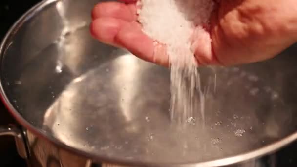 一壶加盐的开水的特写镜头 高加索人的手倒盐 — 图库视频影像