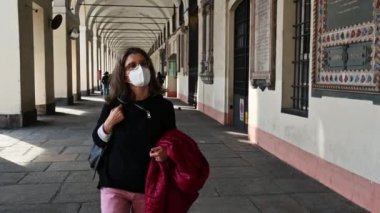 Orta yaşlı bir kadının Torino, İtalya 'nın atari salonlarında rahatça yürüdüğü görüntüler. Koronavirüsten korunmak için maskesi var. Tecritten sonra yeni normal, açık hava rahatlama kavramı.