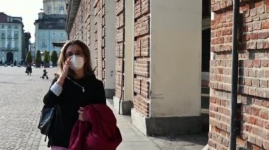 Orta yaşlı bir kadının Torino, İtalya 'daki Piazza Castello' da rahatça yürüdüğü görüntüler. Koronavirüsten korunmak için maskesi var. Tecritten sonra yeni normal, açık hava rahatlama kavramı.