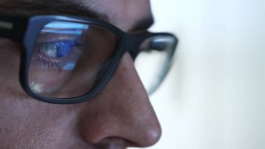 Çalışan bir yazılım mühendisinin gözündeki makro: bakışlar ekrana, gözlüklerin lensine odaklanmış yansımayı görüyoruz. Doğru lensteki net ve kristal berraklığında görüntü. Seçici odak