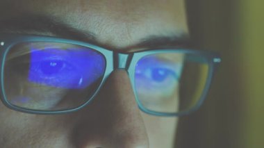 Çalışan bir yazılım mühendisinin portresini yakından incele: gözler ekrana odaklanmış, gözlüklerin lenslerine yansımasını görüyoruz. Eski sinüs efekti.