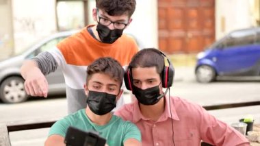 Bir grup arkadaş bir barın masasından yayın yapıyor. Koronavirüse karşı kendilerini korumak için maskeleri var. Yeni normal kavram, arkadaşlık ve teknoloji kullanımı.