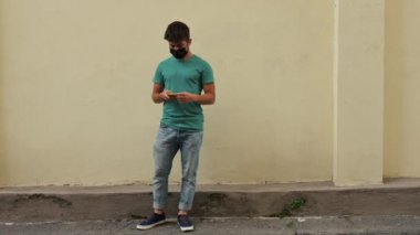 Genç arkadaşlar dirseklerini ve ayaklarını çarpar ve selamlaşırlar. Koronavirüsten korunmak için maskeyi kullanıyorlar. Sosyal uzaklık ve arkadaşlık kavramı.