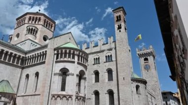 Trento, Trentino, İtalya, Haziran 2021. Güzel bir yaz gününde San Vigilio Katedrali 'nin üç çeyreklik gerisindeki güzel bir kamera görüntüsü. Yanındaki çan kulesi sarı bir bayrak altında kaldı..