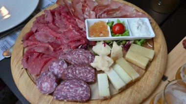 Soslara eşlik etmesi için Trentino spesiyaliteleri ile birlikte iştah açıcı bir tabak soğuk et ve çeşitli peynirler. Bir el bir parça peynir kapar. Tipik ve sağlıklı İtalyan yemeği kavramı.