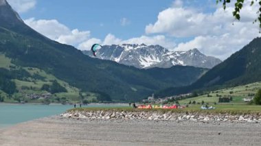 Rsia Gölü, Trentino, İtalya. Göl manzarasının güzel görüntüleri, uçurtma sörfü yapanlar için başlangıç alanını görebilirsiniz: renkli yelkenler dikkat çeker.