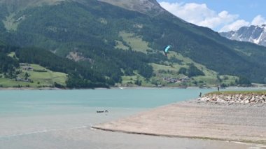 Rsia Gölü, Trentino, İtalya. Göl manzarasının güzel görüntüleri, uçurtma sörfü yapanlar için başlangıç alanını görebilirsiniz: renkli yelkenler dikkat çeker.