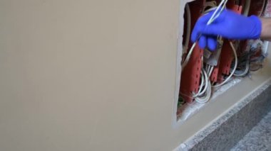 Bir telefon bağlantı kutusu açıldı: Ağ operatöründen bir teknisyen bir apartmanın veri ağına bağlanmak için boruya optik fiber yerleştiriyor.